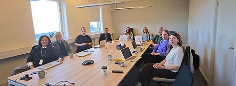 Personer sitter runt ett konferensbord i ett mötesrum.