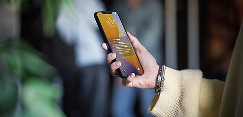 En person håller upp en mobiltelefon med en varningsnotis på skärmen.